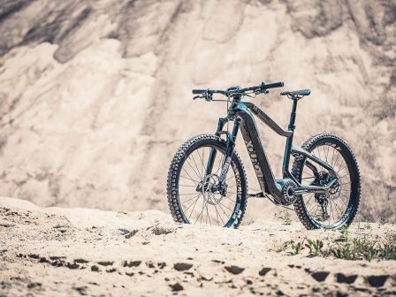 A mountain bike is positioned on rocky terrain with a blurred mountainous background in the image.