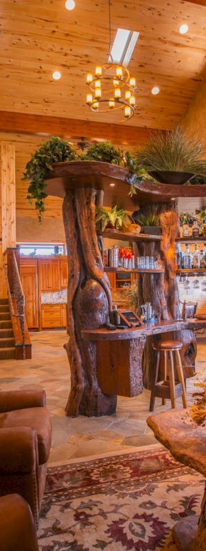 A cozy living room with wooden decor, sofas, a bar area, and warm lighting, featuring rustic and earthy designs.