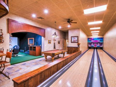 The image shows an indoor recreational space with a bowling alley, pool table, and a putting green area at the back.