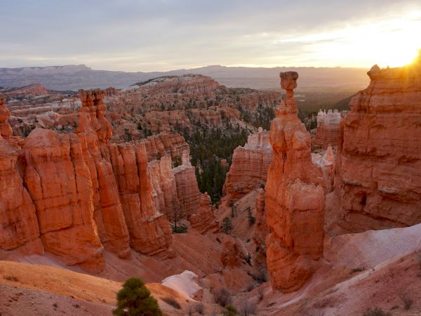 The image shows a stunning view of Bryce Canyon at sunrise, with orange hoodoos and a vibrant sky, capturing natural beauty dramatically.