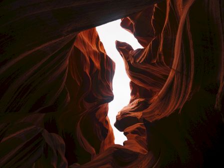 The image shows the interior of a canyon with light filtering through, highlighting the red rock formations.